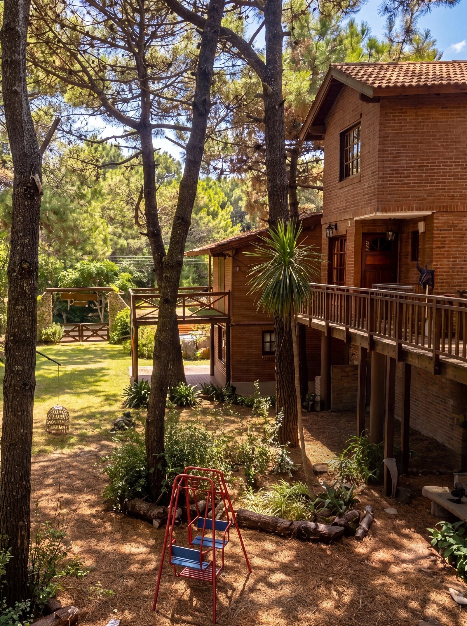 Jardín del complejo con pinos altos y juegos para chicos